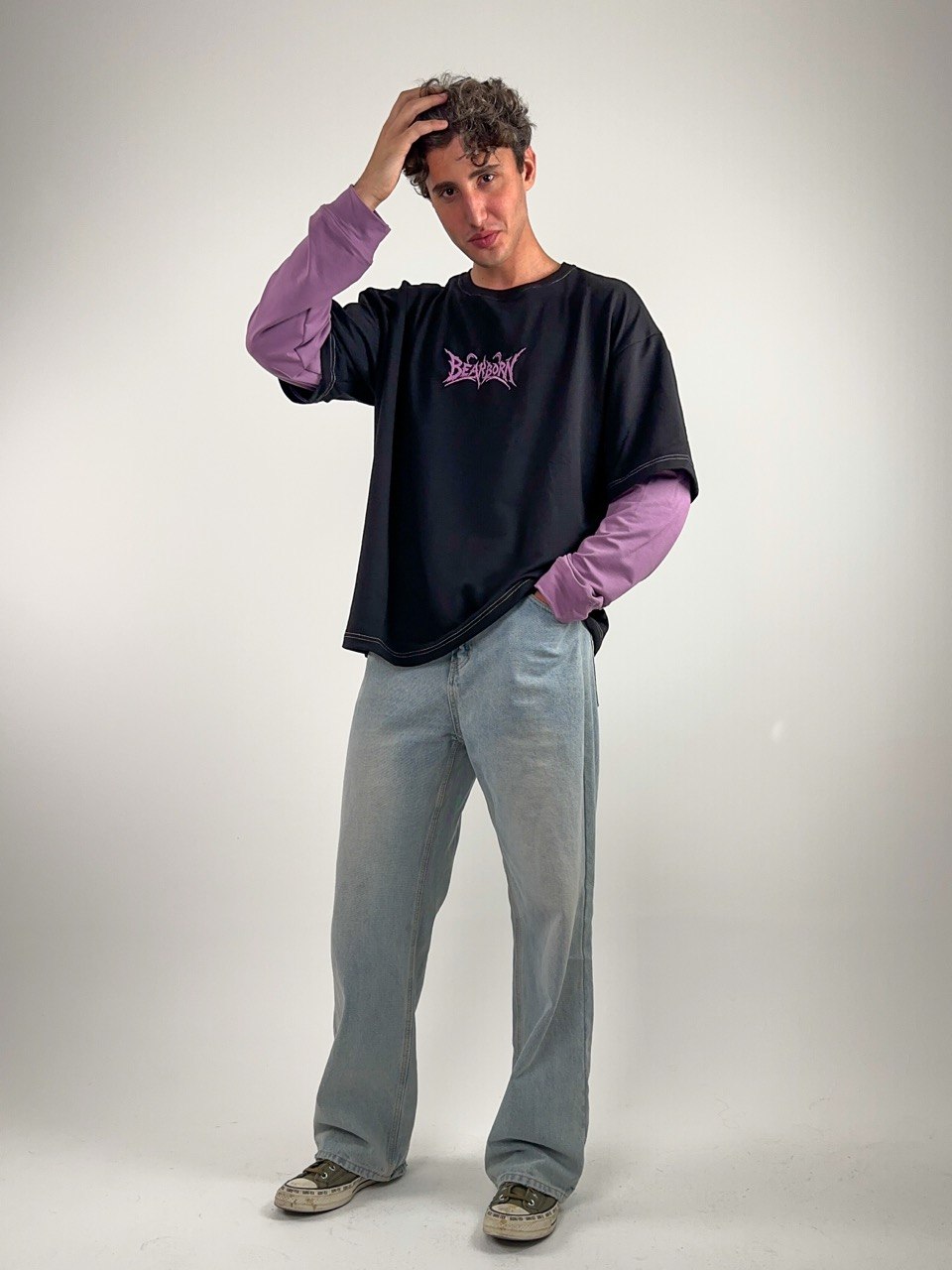 A model in the black Y2K Double Layer Tee with lavender sleeves, standing against a studio backdrop